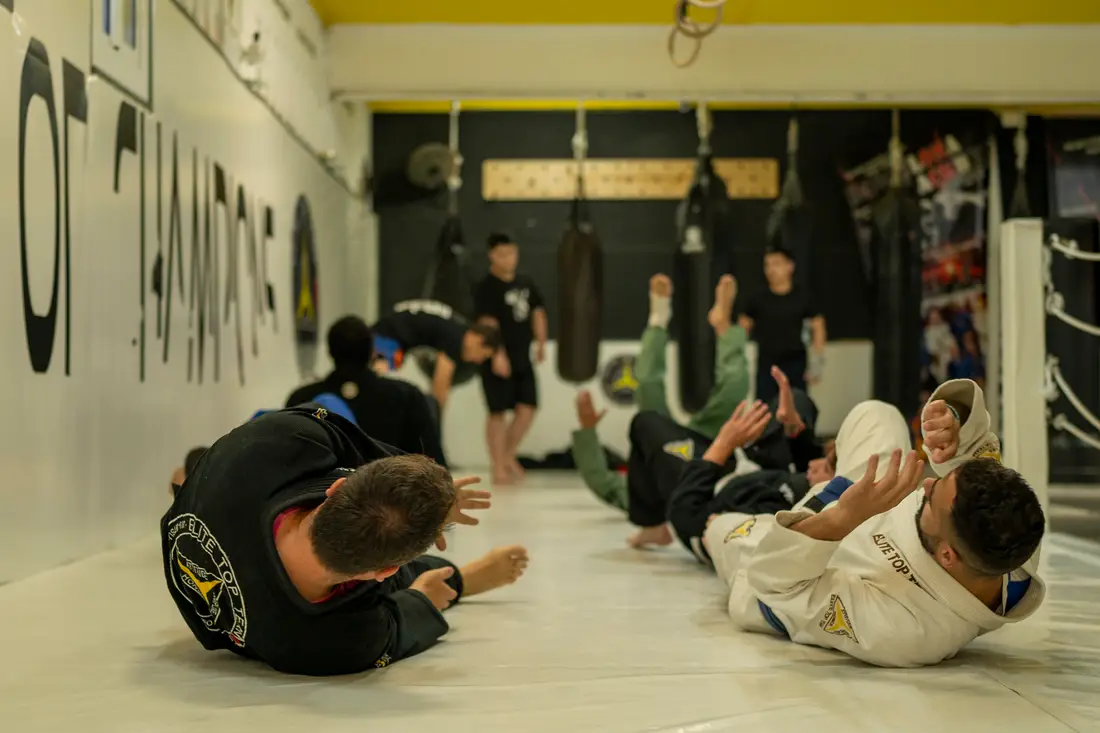 Classe d'adults escalfant sobre el tatami d'Elite Top Team